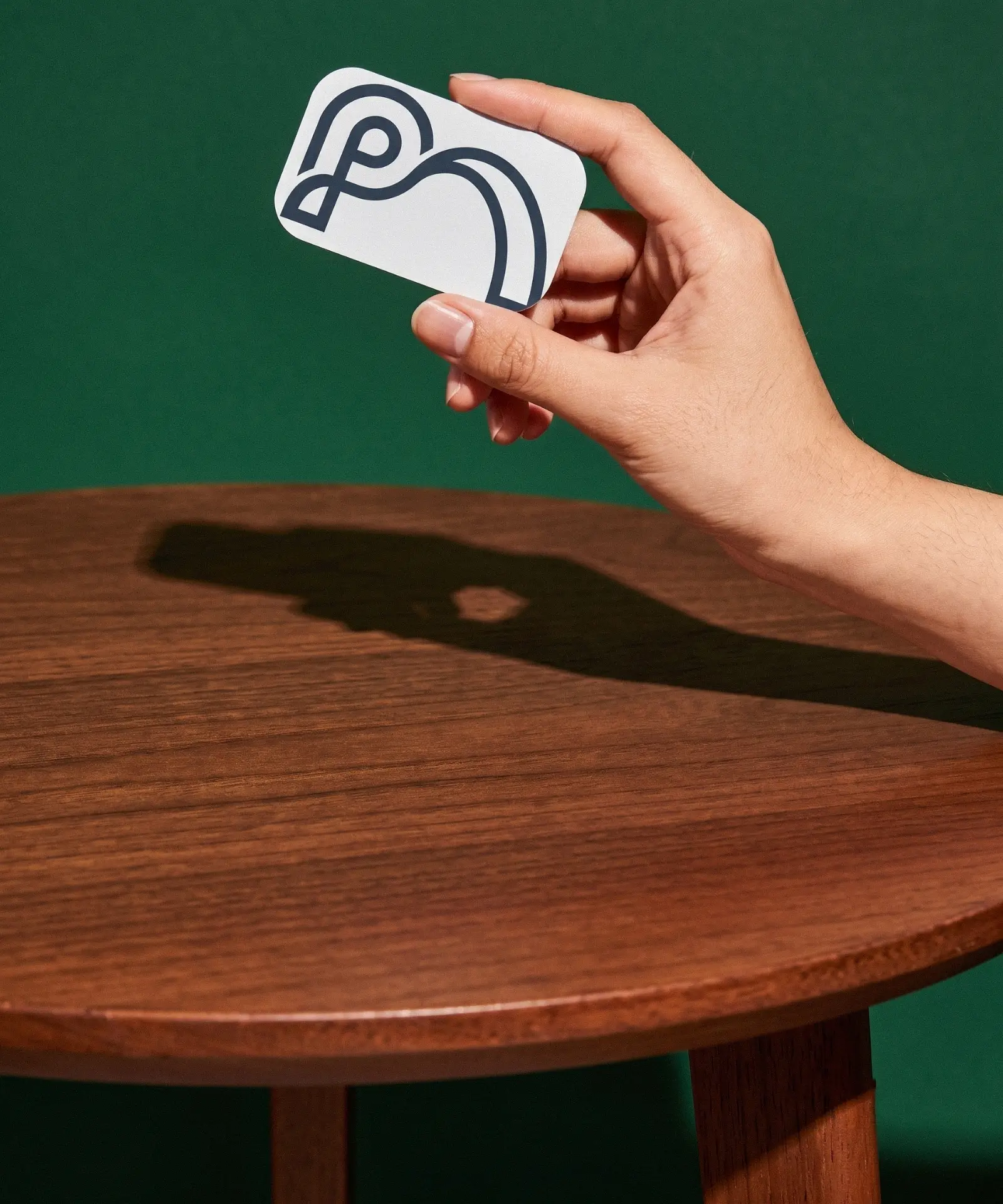 Praxis Assist business card held in hand against a deep green backdrop