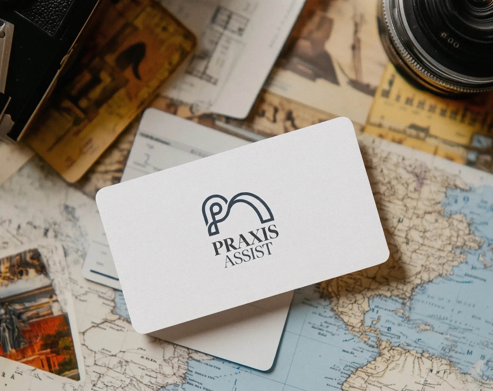 Praxis Assist business card on a vintage map with travel photographs and a camera lens
